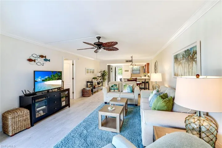 Living area featuring wood finished floors, ceiling fan, and ornamental molding