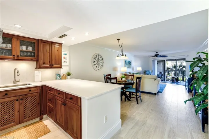 Kitchen featuring crown molding, pendant lighting, a peninsula, open floor plan, and light wood-style flooring