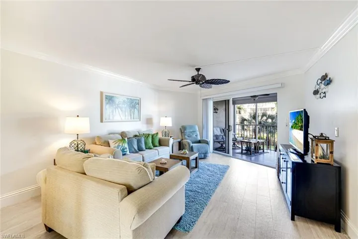 Living area featuring ornamental molding, light wood-style floors, and a ceiling fan