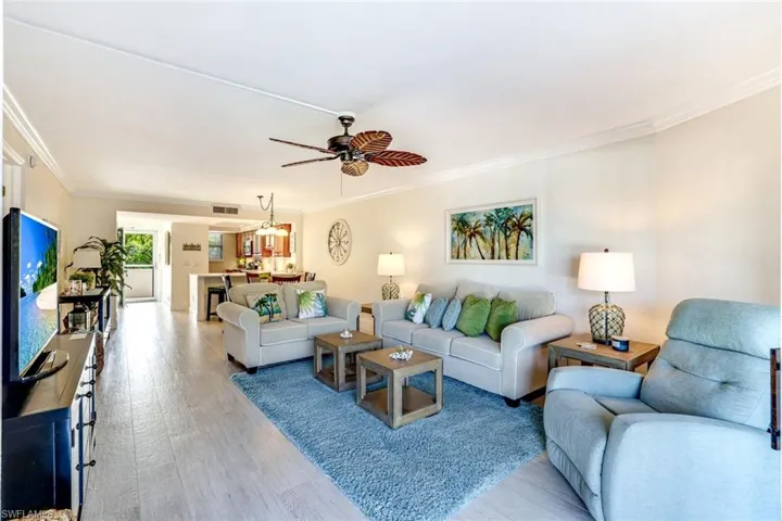Living area with crown molding, a ceiling fan, and wood finished floors