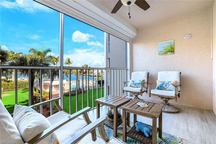 Sunroom / solarium with a ceiling fan, a balcony, a water view, and healthy amount of natural light