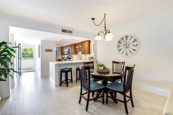 Dining room with light wood-type flooring, crown molding, and a chandelier