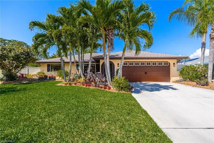 Single story home featuring stucco siding, fence, an attached garage, screened - covered front entrance, and landscaped front lawn.