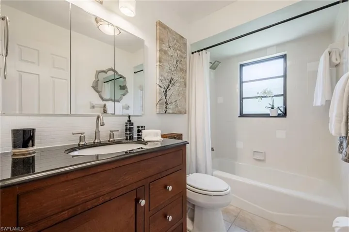 Guest / 2nd Bathroom featuring tile patterned flooring, vanity, tasteful backsplash, shower / tub combo.