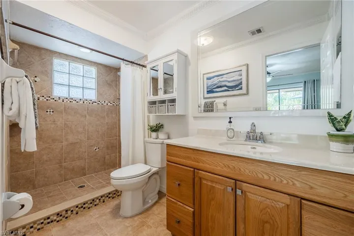 Full bathroom with plenty of natural light, crown molding, tiled shower, and vanity