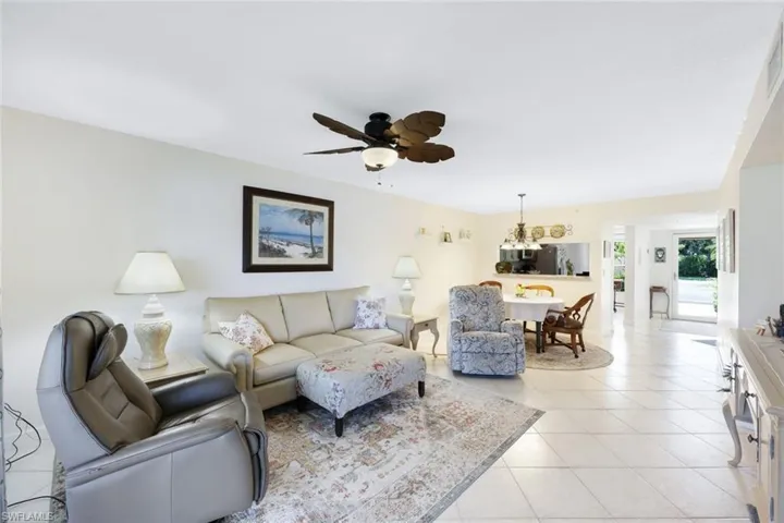Living room featuring ceiling fan with notable chandelier and light tile patterned floors