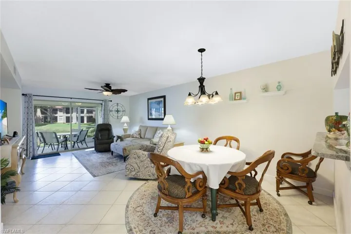 Tiled dining room with ceiling fan with notable chandelier
