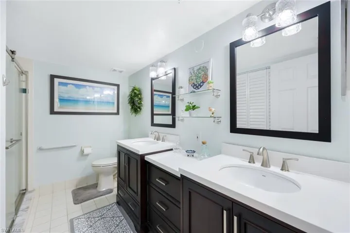 Bathroom featuring tile patterned flooring, toilet, and dual bowl vanity