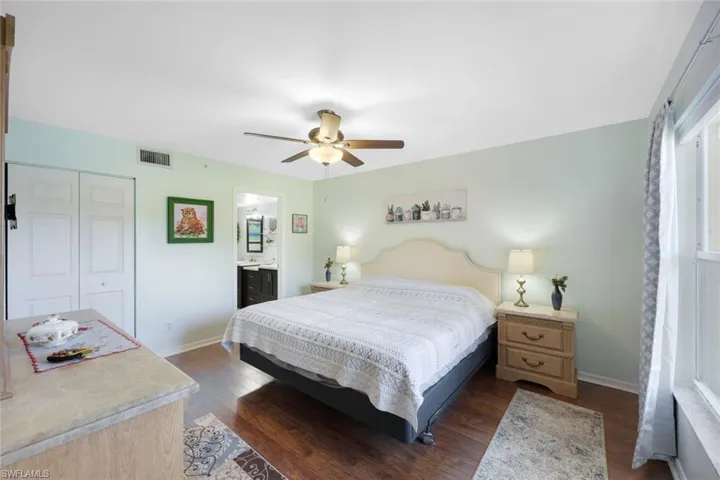 Bedroom with dark hardwood / wood-style flooring, a closet, ensuite bath, and ceiling fan