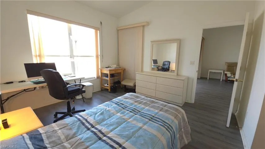 Bedroom with dark hardwood / wood-style flooring and lofted ceiling