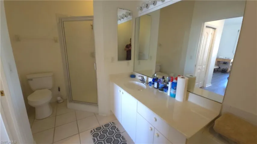 Bathroom with tile patterned flooring, vanity, toilet, and a shower with door