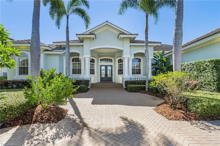 View of front entry with large front porch, double doors, stucco siding and tiled roof.