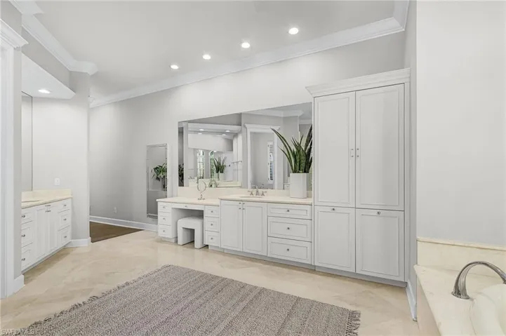 Main bathroom featuring ornamental molding, two sinks, vanities, lots of storage and a tub to relax in, and recessed lighting