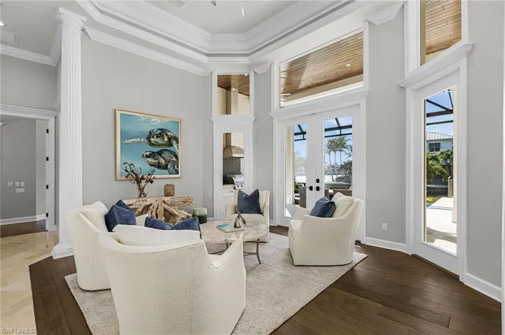 Living room with a high ceiling, french doors, crown molding, and wood finished floors