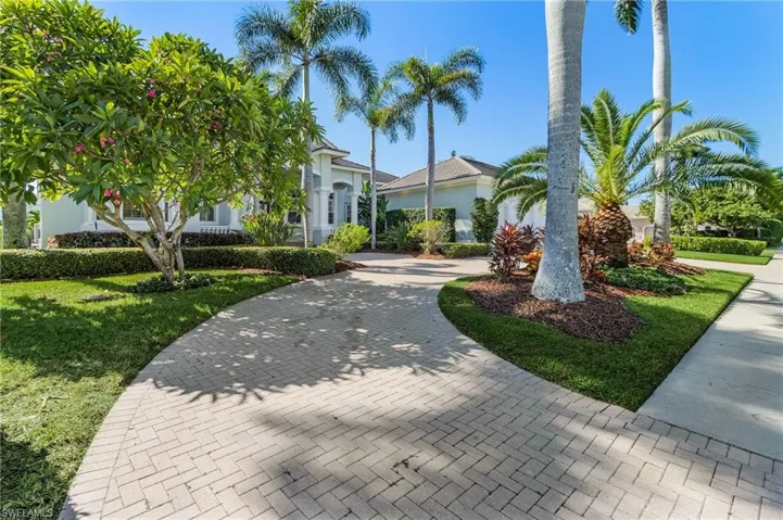 View of circular driveway, palm trees and manicured lawn