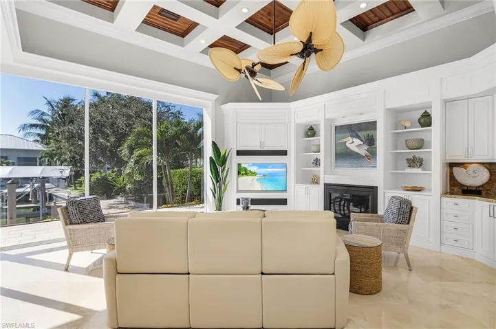 Familly room featuring rich wood coffered ceiling, gas fireplace, wet bar, zero-corner sliders and view of the boats or Roberts Bay.