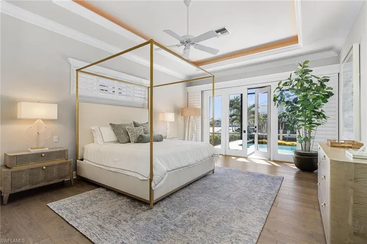 Main bedroom featuring french doors, a ceiling fan, ornamental molding, Vietnamese wood floors, and lighted tray ceiling