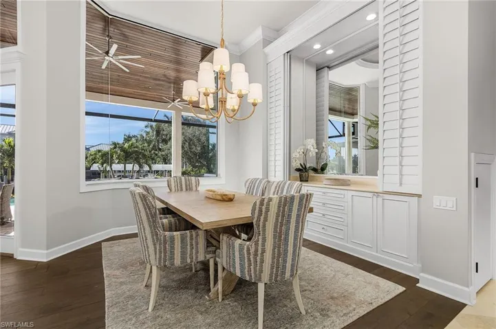 Dining room with ornamental molding, Vietnamese wood floors, recessed lighting, built in cabinets and a chandelier