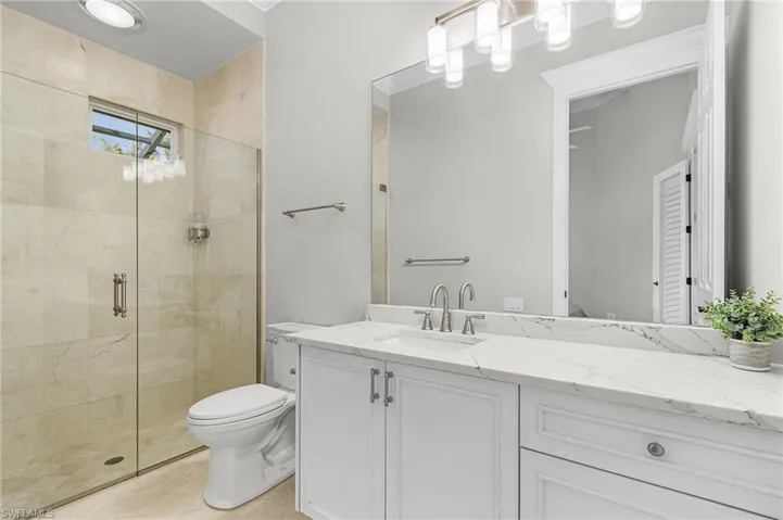 Full bathroom featuring a shower stall, vanity, and marble floors.