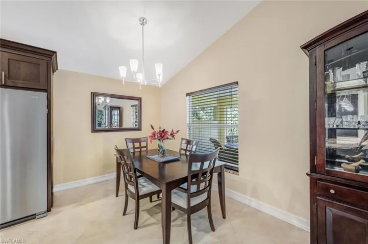 Dining area with light tile floors, vaulted ceiling, and an inviting chandelier