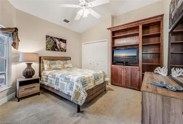 Carpeted bedroom with a closet, ceiling fan, and vaulted ceiling