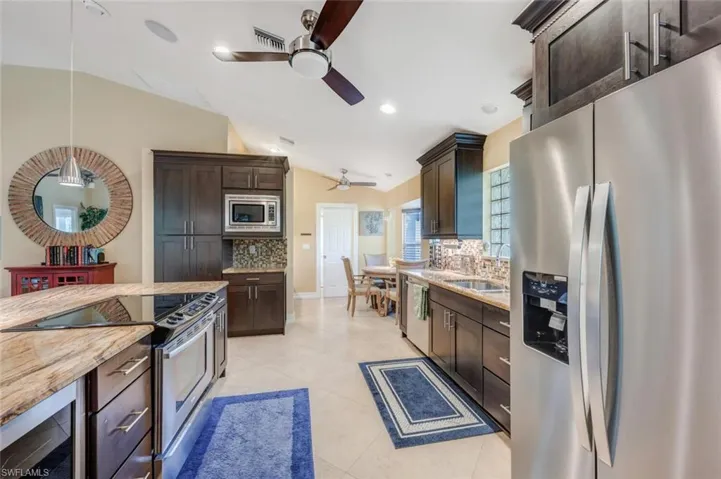 Kitchen featuring ceiling fan, light tile floors, backsplash, and appliances with stainless steel finishes