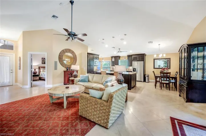 Living room featuring vaulted ceiling, ceiling fan, and light tile floors