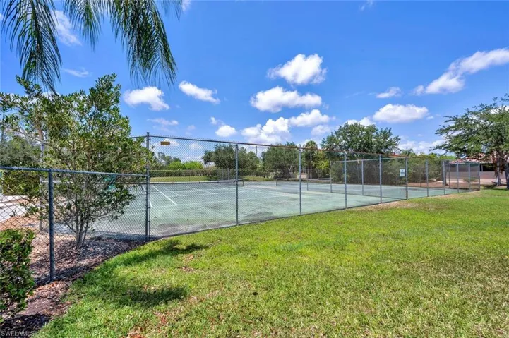View of tennis court with a lawn