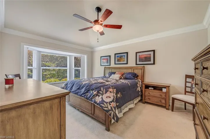 Carpeted bedroom with crown molding and ceiling fan
