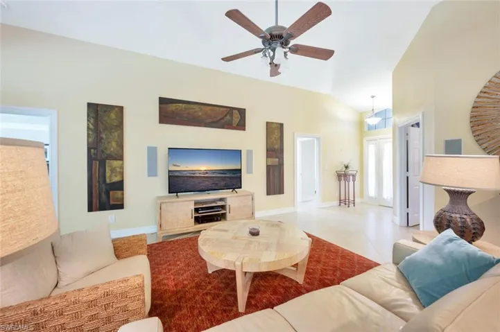 Living room with high vaulted ceiling, tile flooring, and ceiling fan