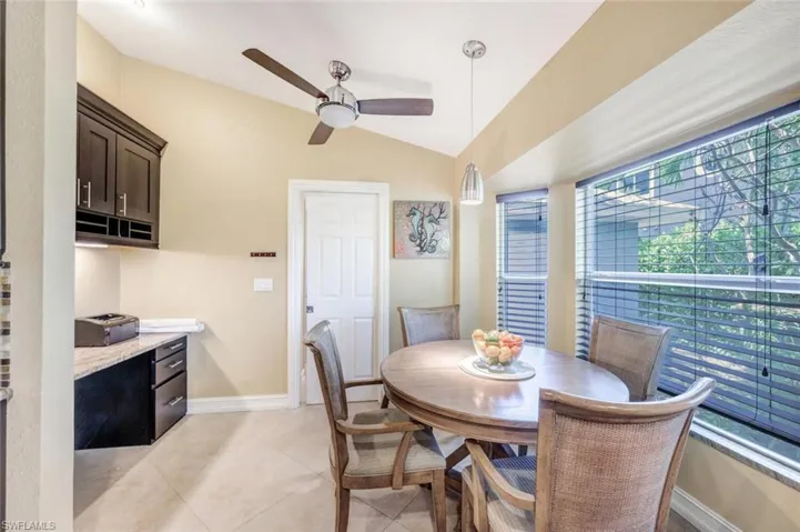 Dining room with ceiling fan, vaulted ceiling, and light tile flooring