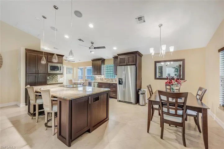 Kitchen with stainless steel appliances, hanging light fixtures, tasteful backsplash, and a kitchen island