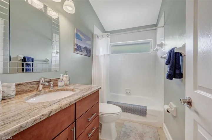 Full bathroom featuring vanity with extensive cabinet space, tile flooring, toilet, and shower / tub combo with curtain