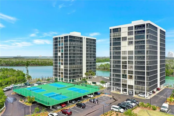View of apartment building / complex featuring uncovered parking and a water view