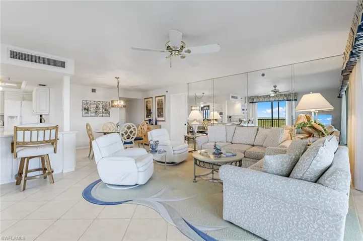 Living area with ceiling fan, light tile patterned floors, and a chandelier