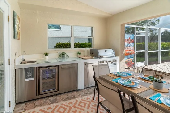 Kitchen with a textured wall, light countertops, beverage cooler, vaulted ceiling, and plenty of natural light