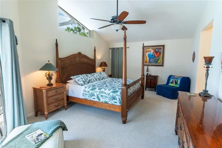 Carpeted bedroom with ceiling fan and high vaulted ceiling