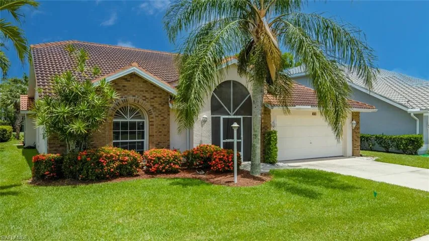 View of front of home with a tile roof, a front lawn, concrete driveway, a garage, and brick siding