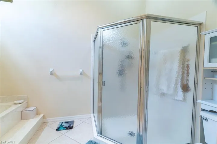 Bathroom featuring light tile patterned floors, a shower stall, and a garden tub