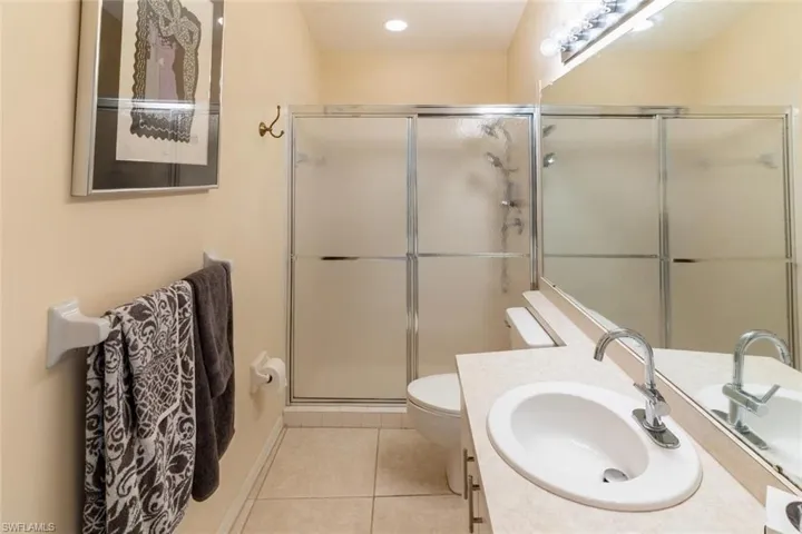 Bathroom featuring vanity, light tile patterned floors, a shower stall, and recessed lighting