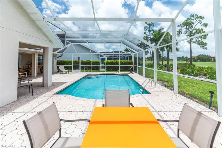 Outdoor pool with a patio, a sunroom, glass enclosure, and a yard