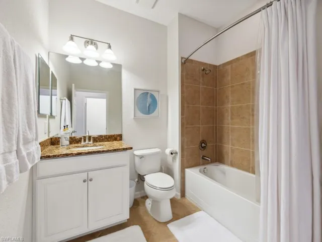 Full bath with shower / tub combo with curtain, vanity, toilet, and tile patterned flooring
