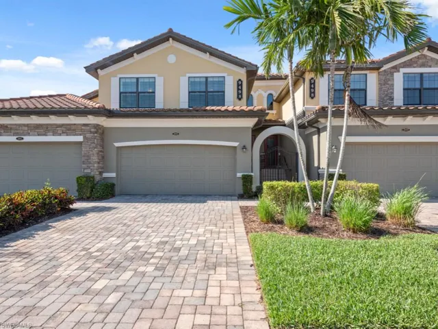 View of front of home featuring a tiled roof, stone siding, a garage, and stucco siding