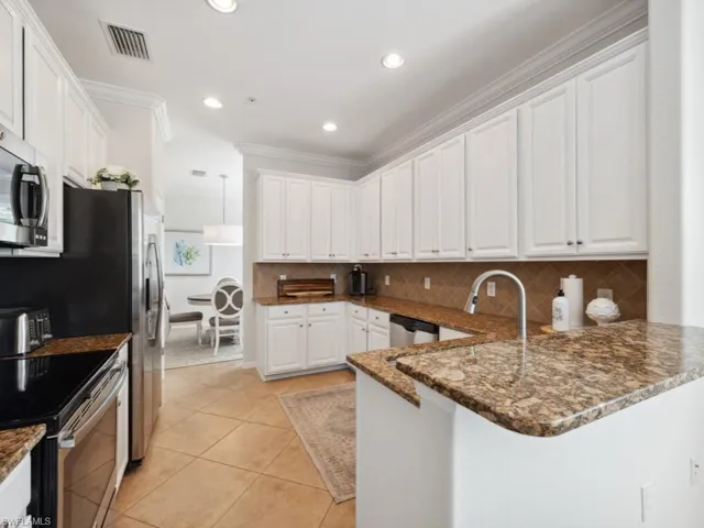 Kitchen with a peninsula, visible vents, white cabinetry, and appliances with stainless steel finishes
