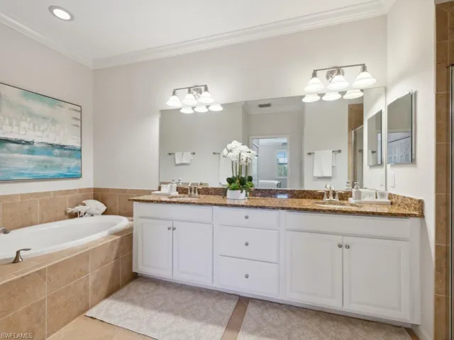 Bathroom with double vanity, crown molding, tiled shower, a bath, and a sink