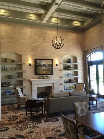 Living room with beamed ceiling, a fireplace, a towering ceiling, a chandelier, and coffered ceiling