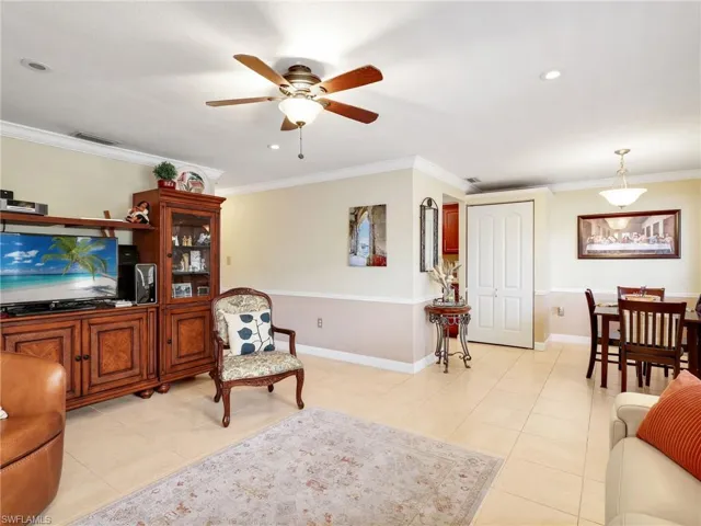 Living room with light tile patterned floors, a ceiling fan, recessed lighting, and crown molding