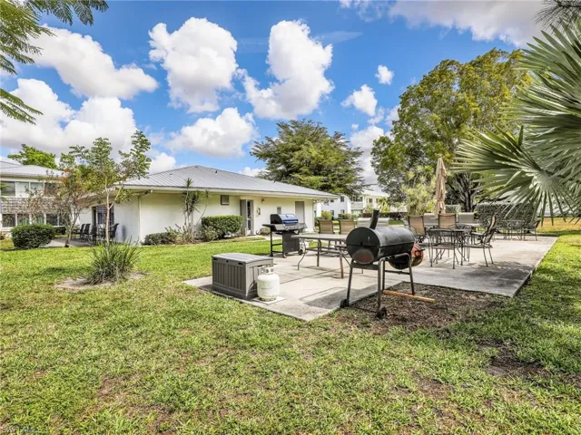 Back of house with a patio, stucco siding, outdoor dining area, and a lawn