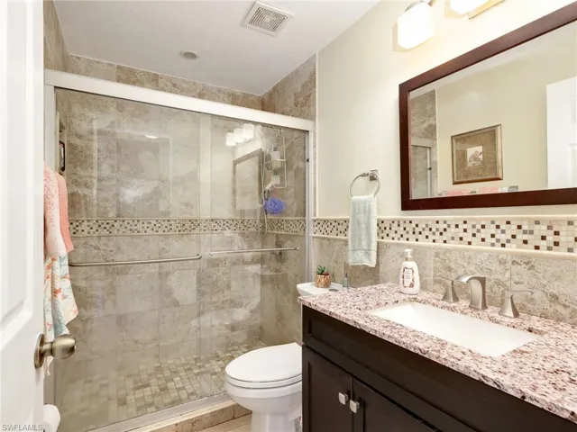 Bathroom with vanity, a stall shower, and tile walls