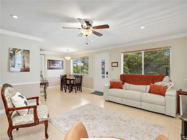 Living room featuring ceiling fan, crown molding, and light tile patterned flooring